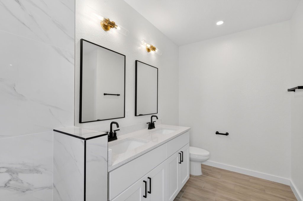 Bathroom vanity with black fixtures and marble-look tile