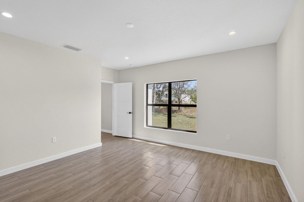 Bright bedroom with wood-look flooring in a completed AM Homes build