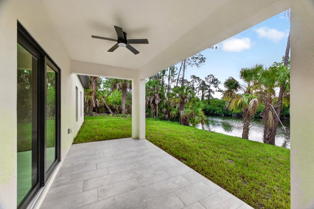 Covered lanai with ceiling fan overlooking the backyard